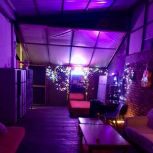 Espacio interior de SW Club Concepción con iluminación violeta, sillones, mesas y decoración íntima que crea un ambiente acogedor y elegante.